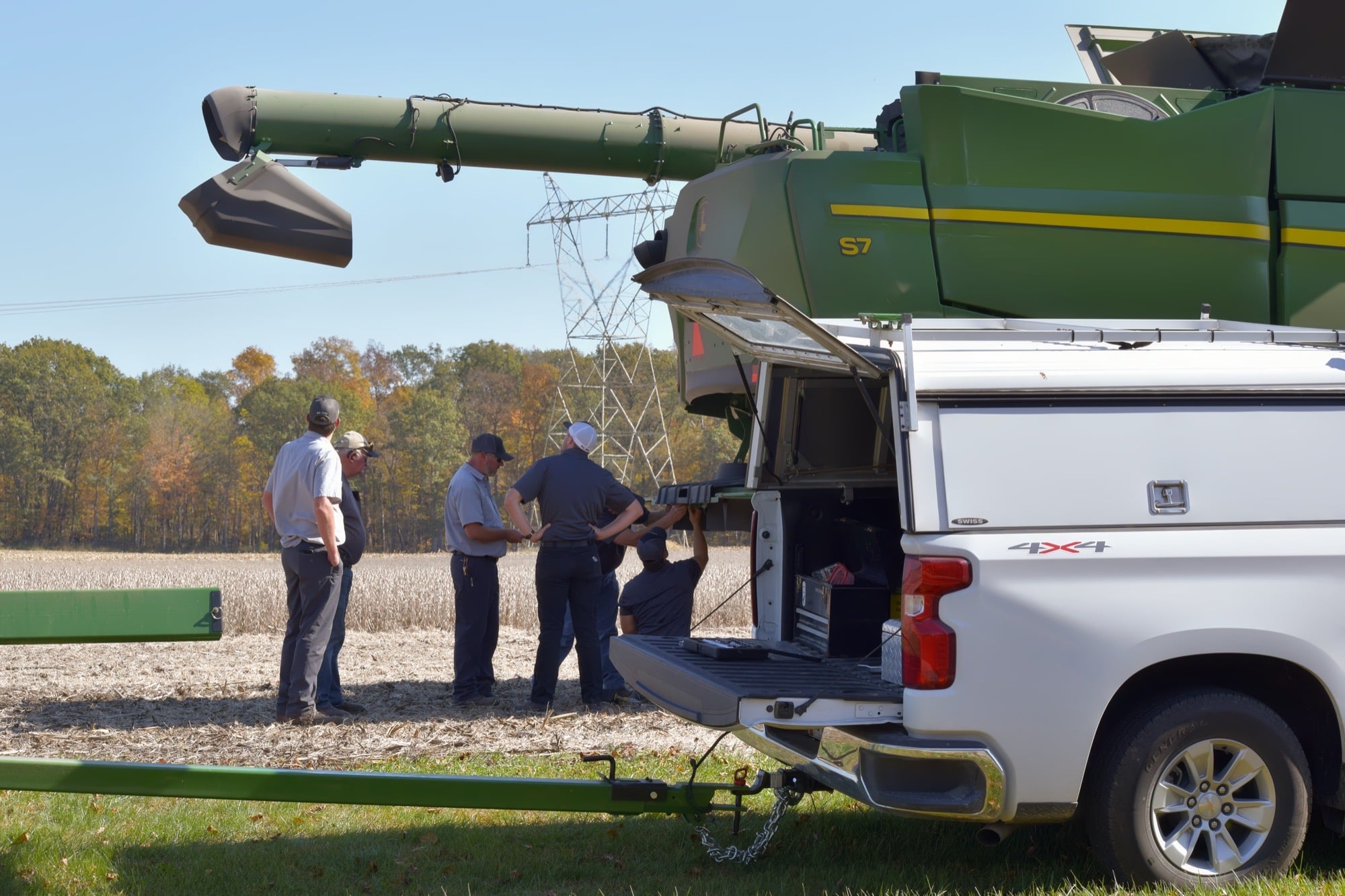 Koenig technicians working with a farmer beside a John Deere S7 combine and a service truck during harvest