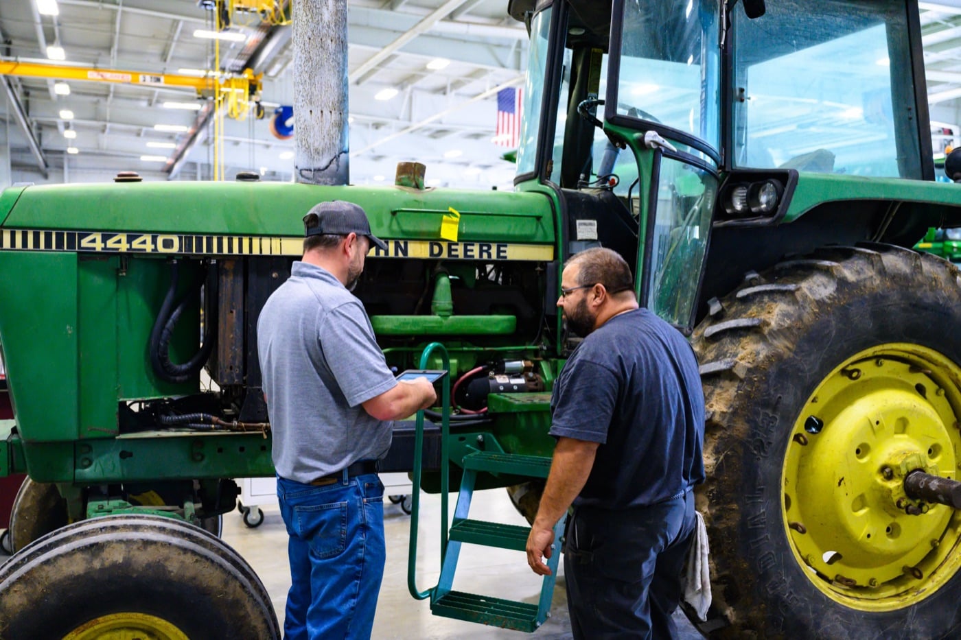 Two Koenig Equipment team members working through a repair on a John Deere 4440 tractor in the Greenville, Ohio service shop