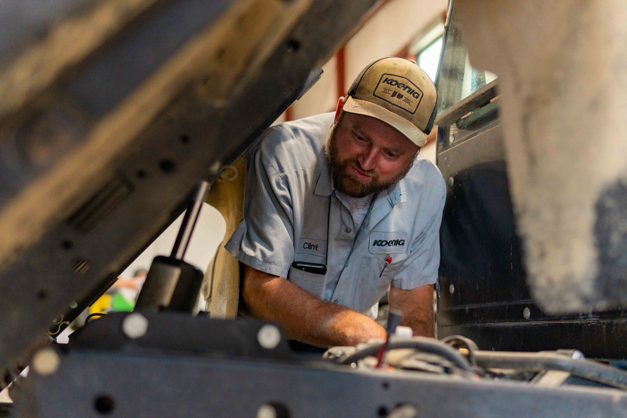 A Koenig Equipment service technician working under the hood of a machine in the Botkins, Ohio service shop