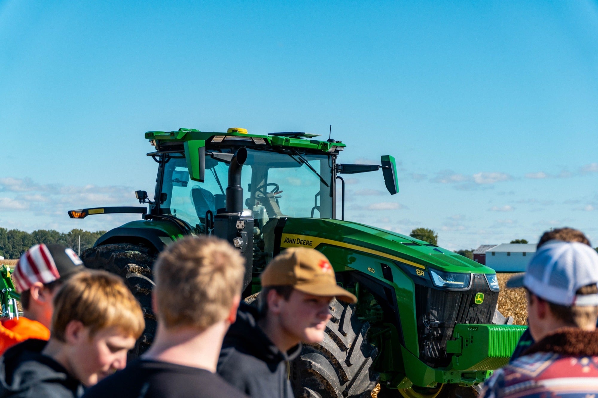 Young people getting a close look at a John Deere 8R autonomous tractor at a Koenig Equipment field event